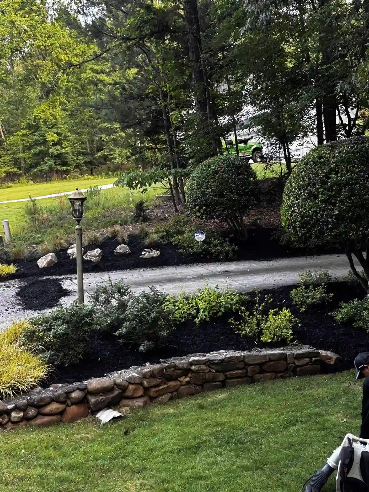 Fresh black mulch installation with stone retaining wall at a residential property in Woodstock, GA